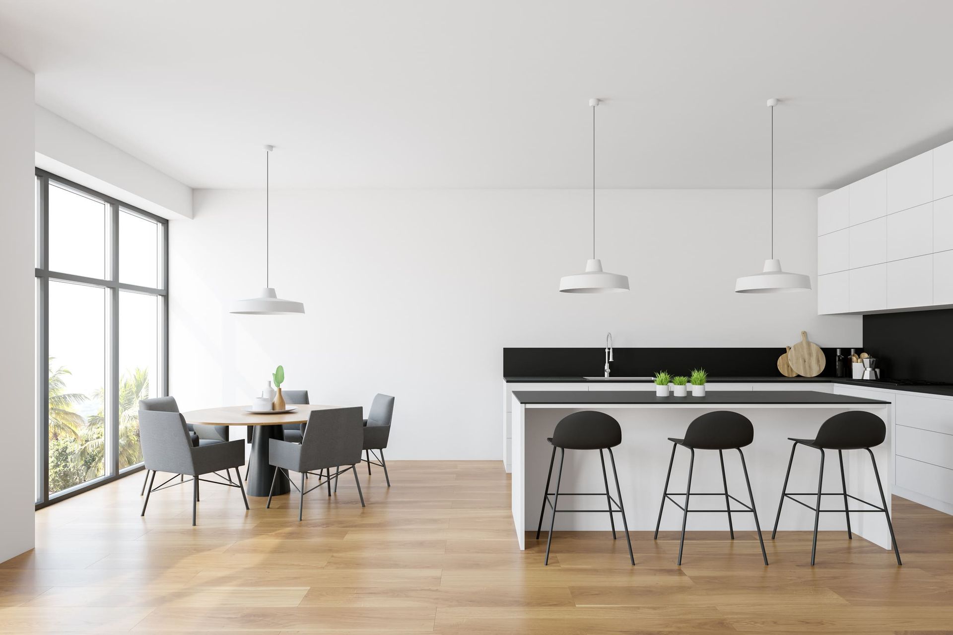 Una cocina moderna con gabinetes blancos y encimeras negras y un comedor con mesa y sillas.