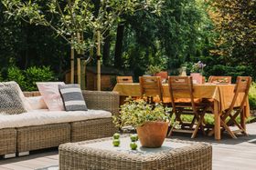 Un patio con un sofá, una mesa, sillas y una planta en maceta.