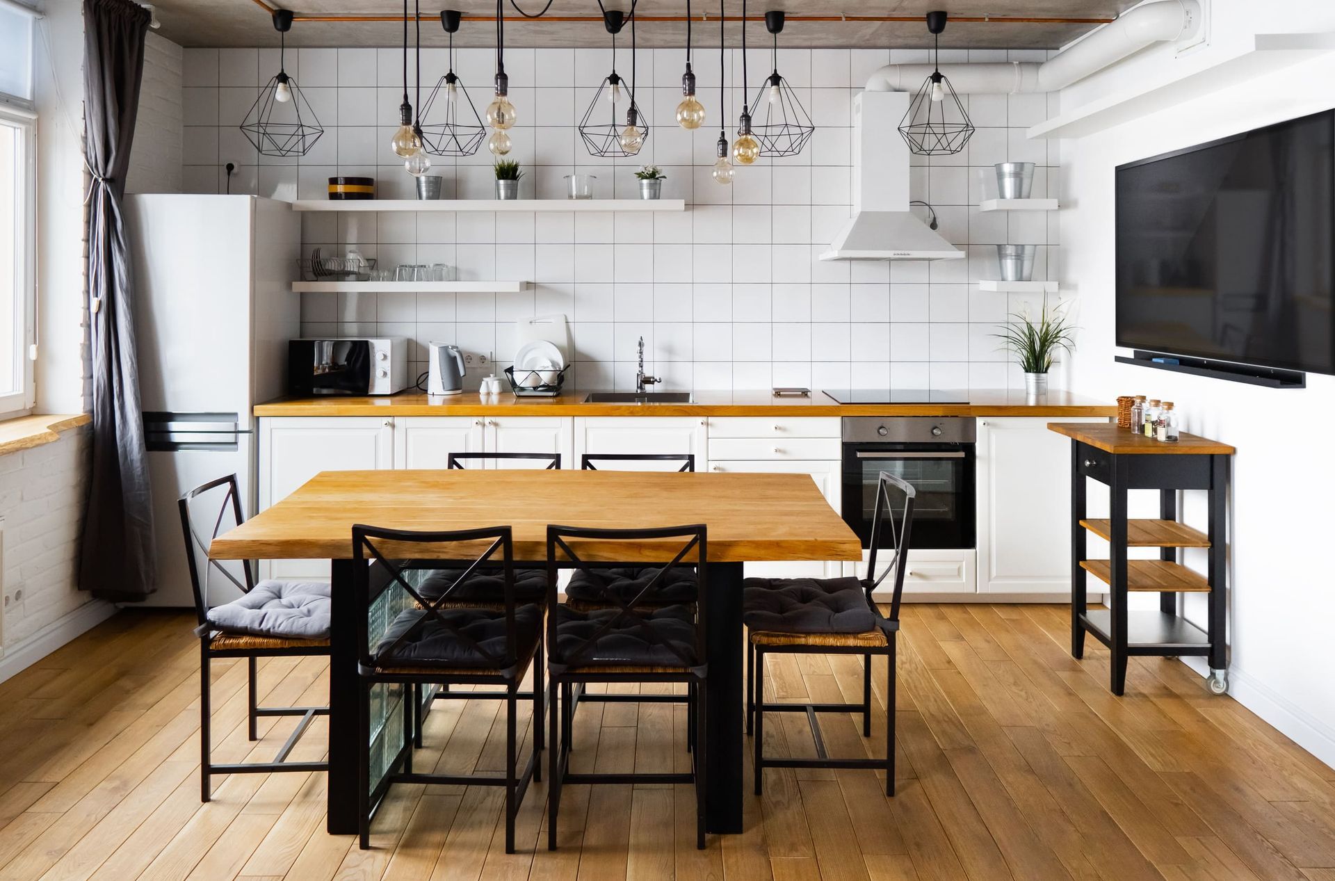 Una cocina con mesa y sillas de madera y un televisor de pantalla plana.