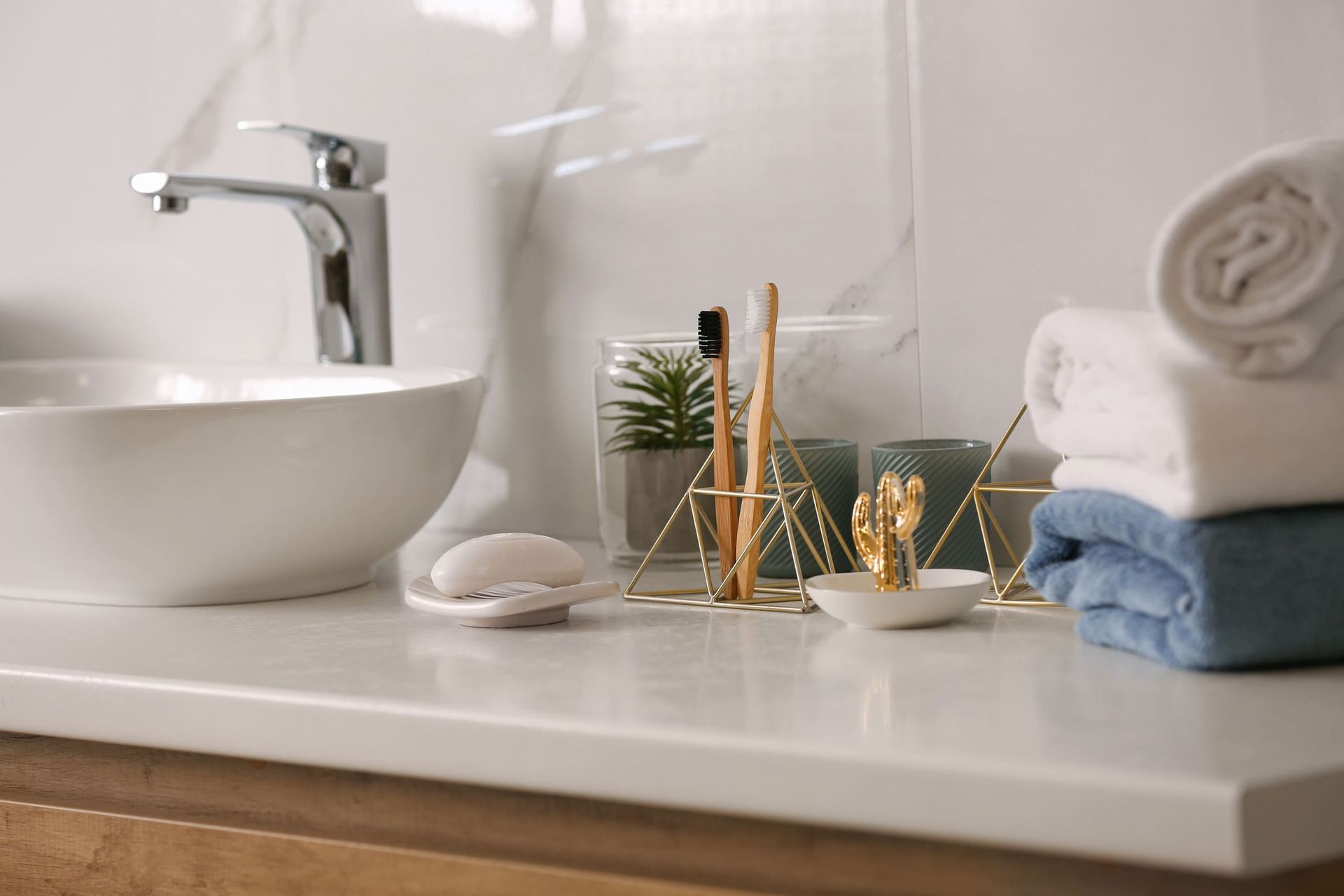 Un mostrador de baño con lavabo, toallas, cepillos de dientes y jabón.