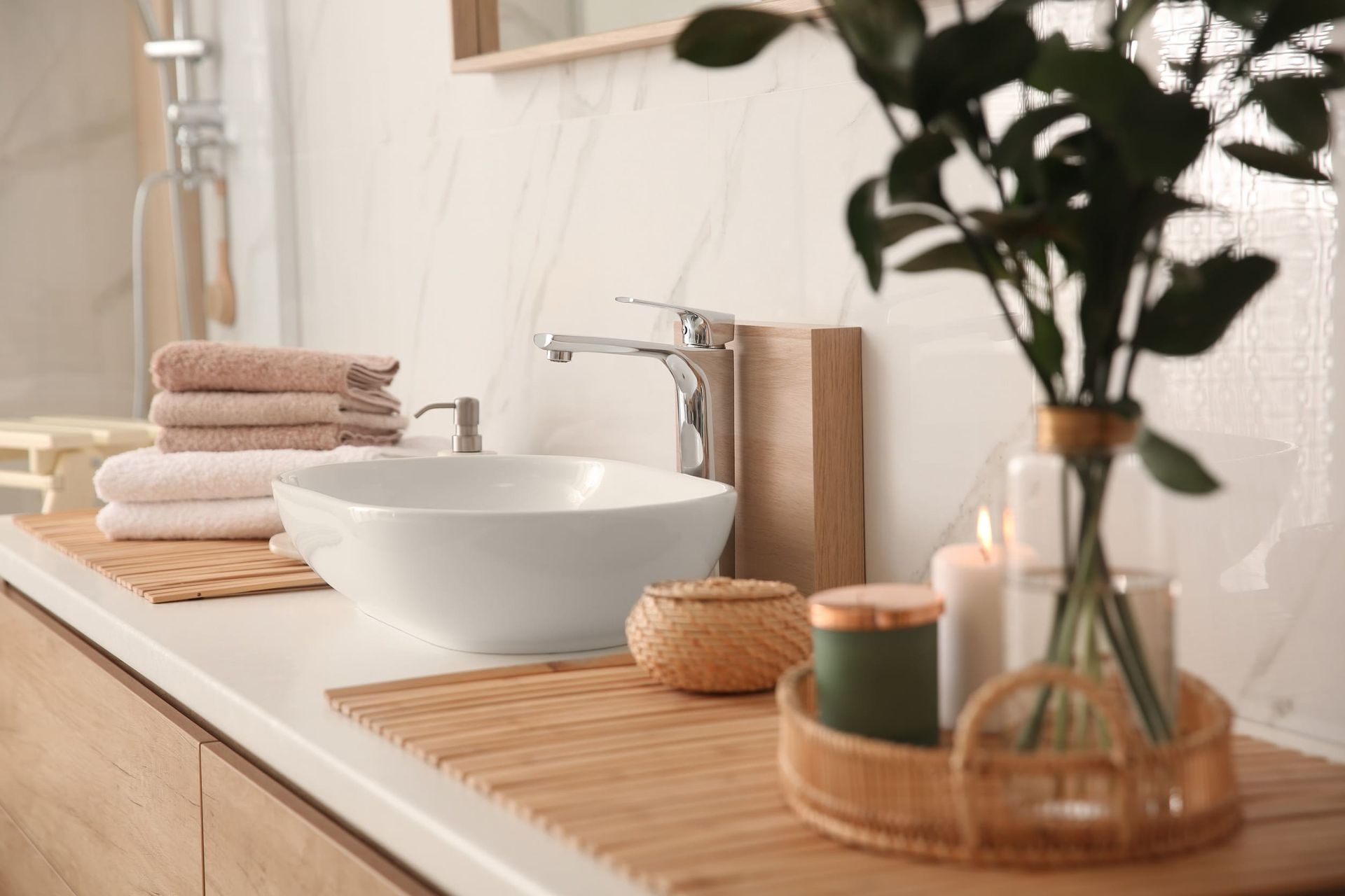 Un baño con lavabo, toallas, velas y una planta en la encimera.
