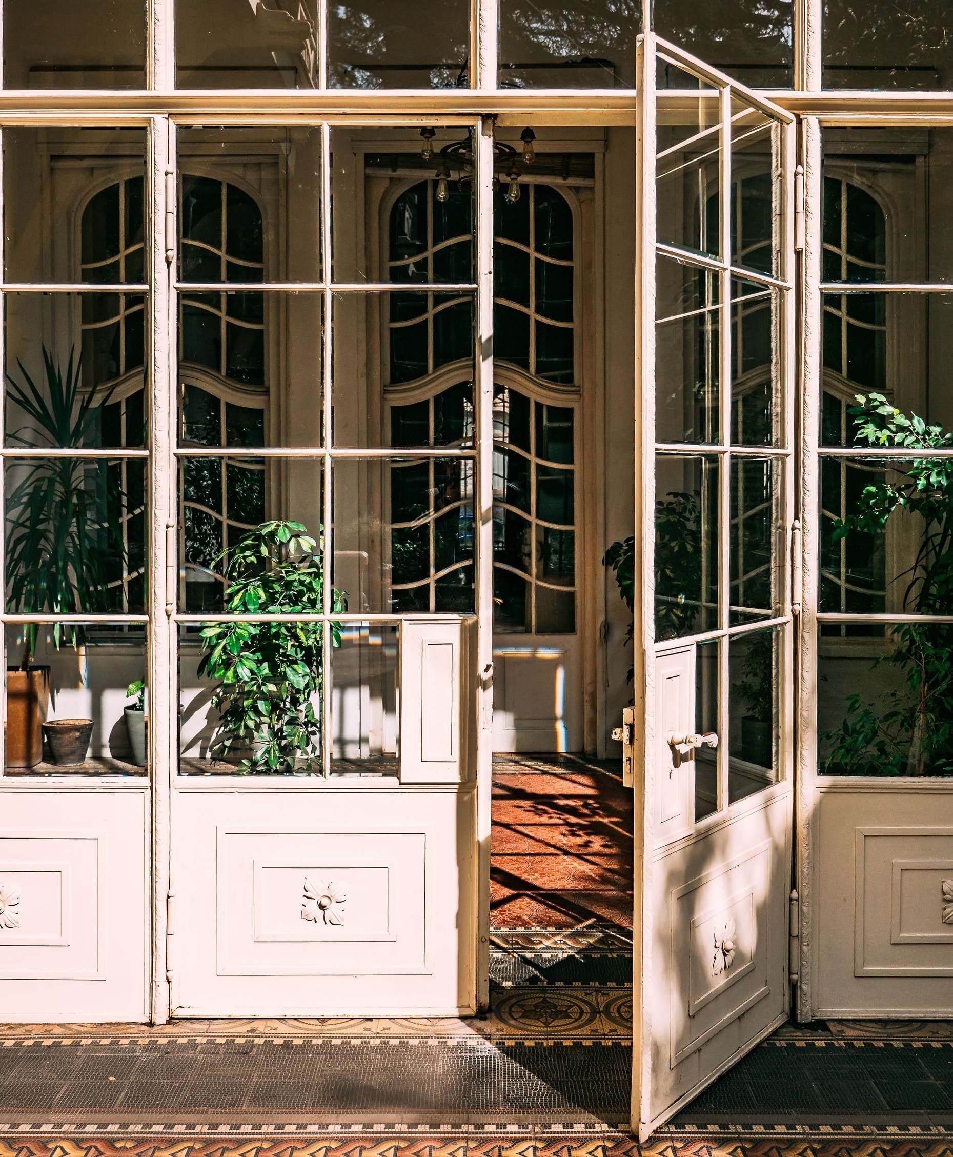 Una puerta blanca con muchas ventanas está abierta.