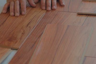 Una persona está instalando un piso de madera en una habitación.