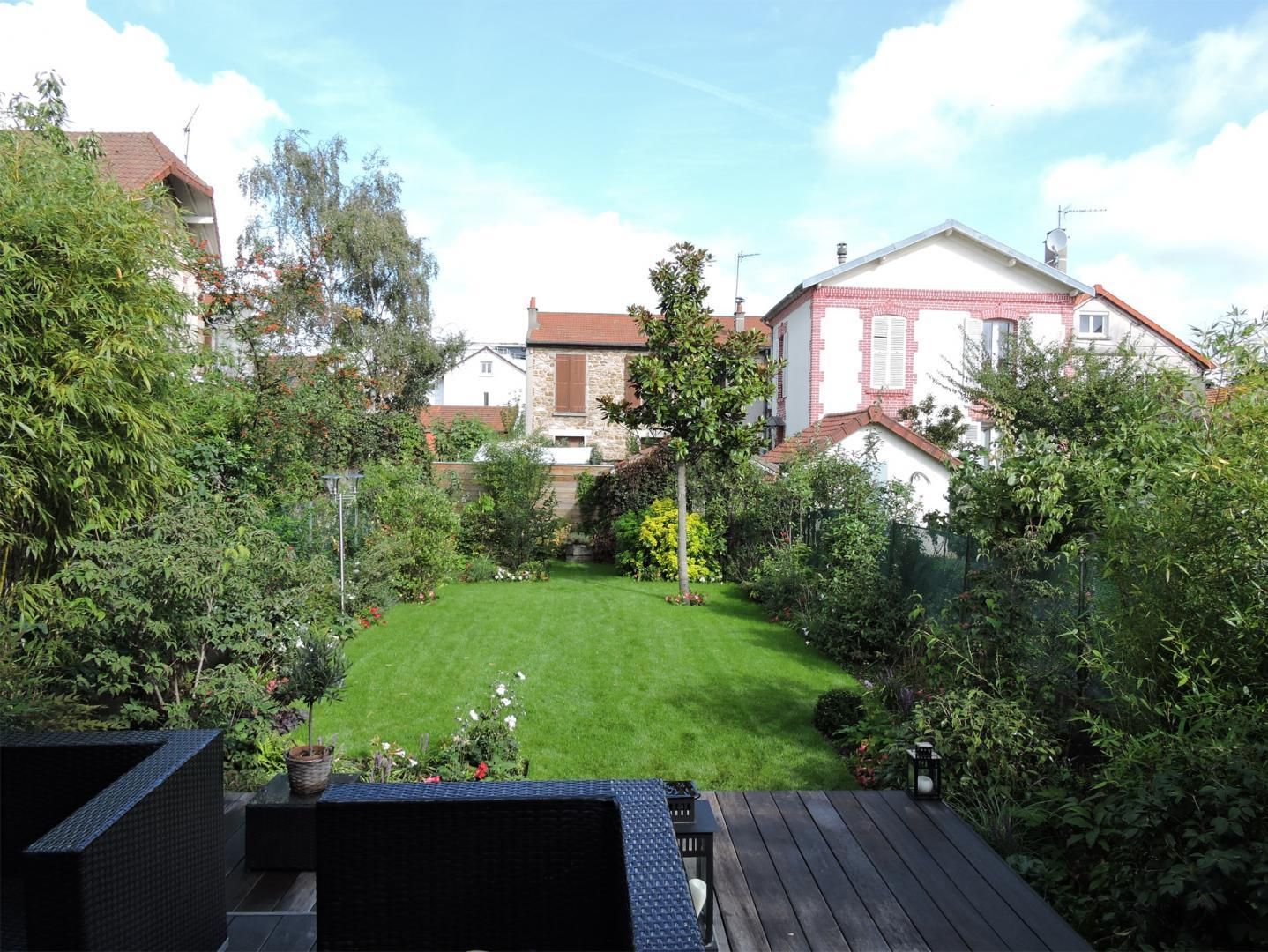 Une pelouse et une terrasse en bois devant une maison