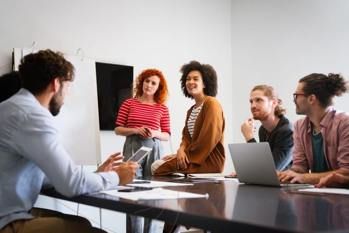 Un grupo diverso de compañeros de trabajo debate ideas de forma colaborativa durante una reunión.
