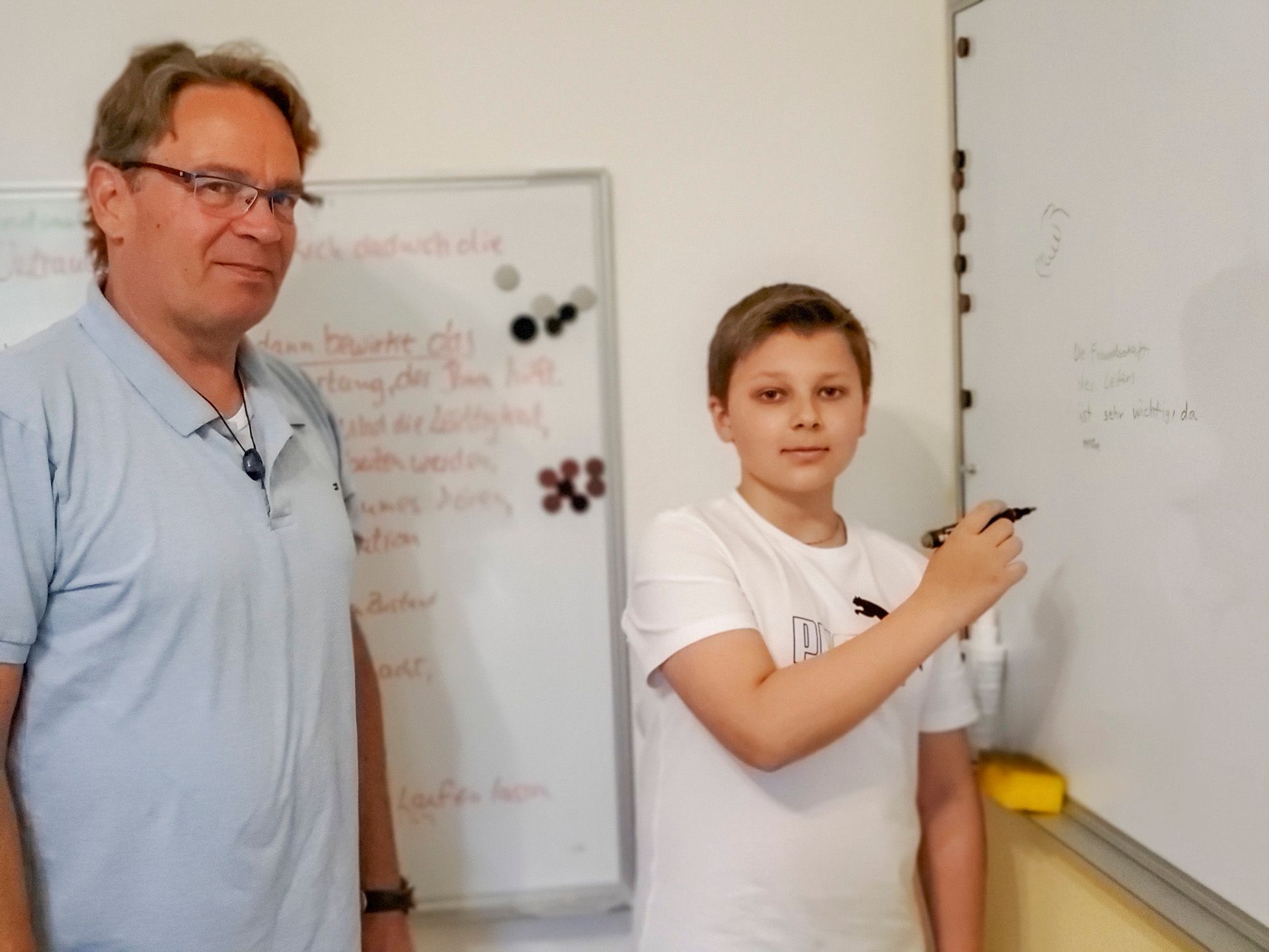 Ein Mann und ein Junge stehen vor einer weißen Tafel