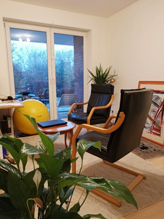 Ein Wohnzimmer mit zwei Stühlen, einem Tisch und einem gelben Ball.