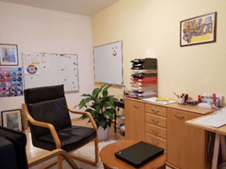 Ein Zimmer mit einem Stuhl und einem Laptop auf einem Tisch