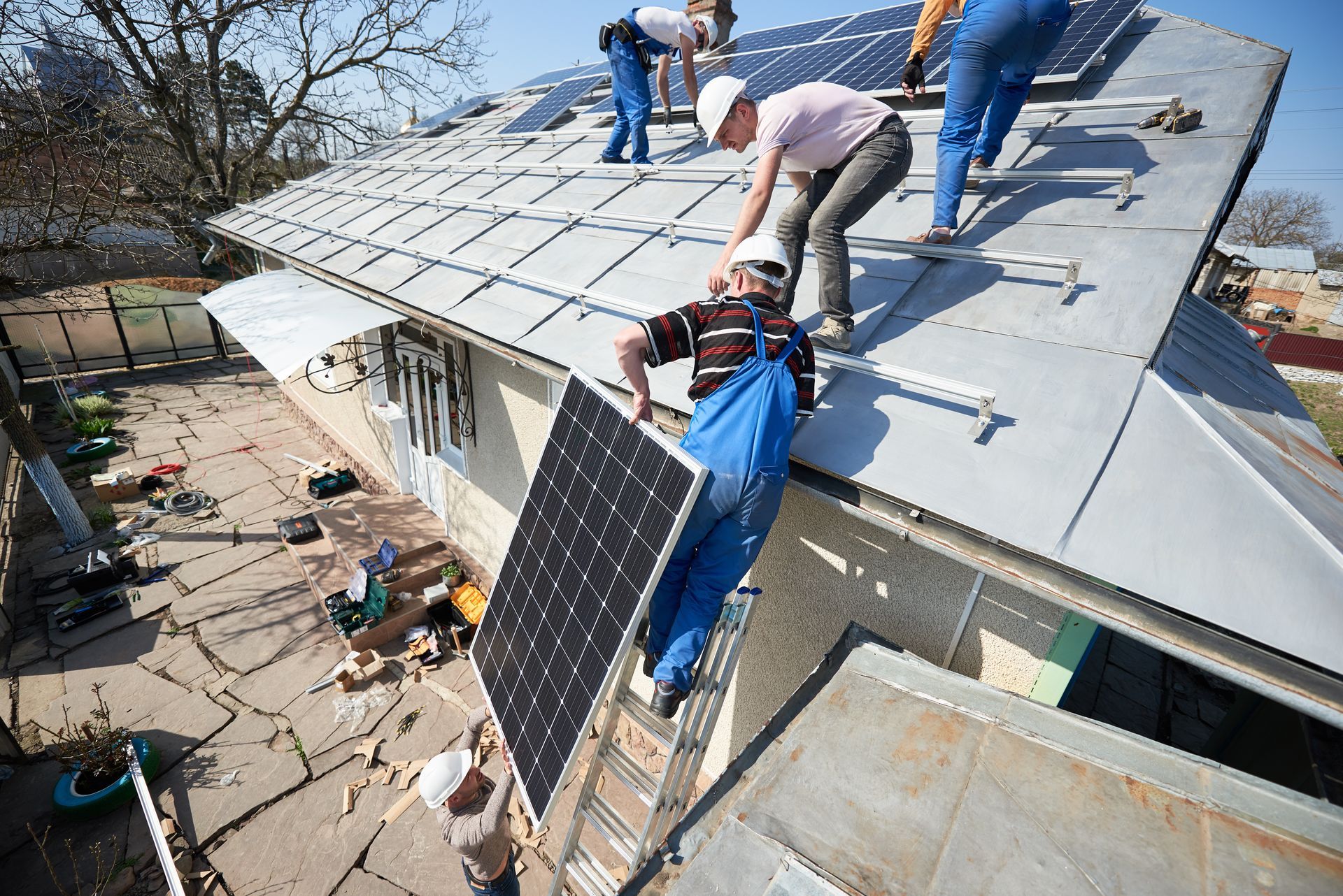 Arbeiter installieren Solarpaneele auf einem schrägen Dach eines Hauses