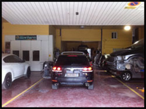 Un coche negro está aparcado en un garaje con otros coches.