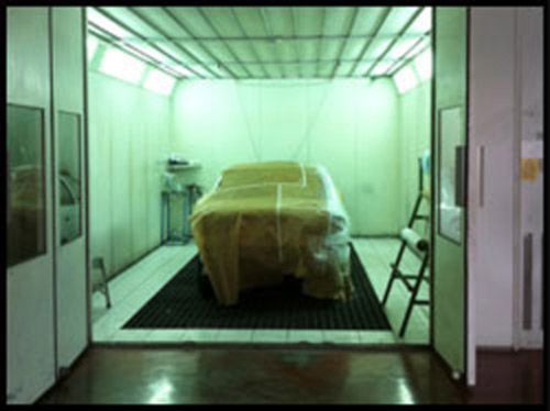Un coche está envuelto en plástico en una cabina de pintura.