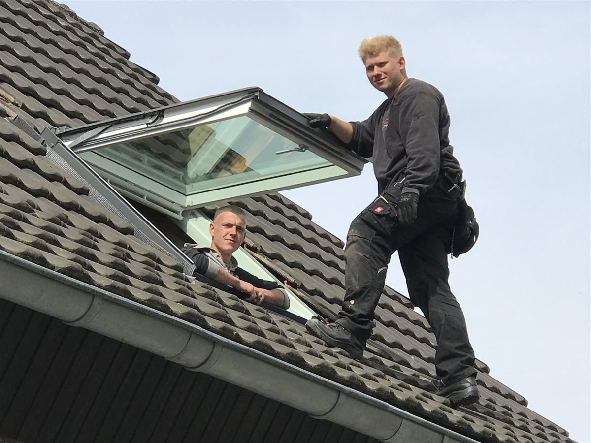 Zwei Männer arbeiten auf dem Dach eines Hauses