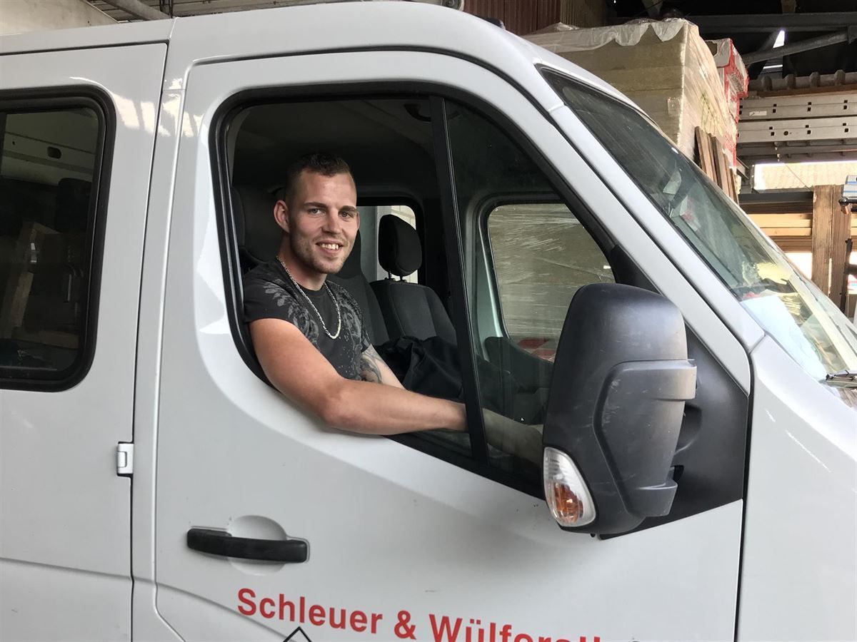 Ein Mann sitzt auf dem Fahrersitz eines weißen Lieferwagens