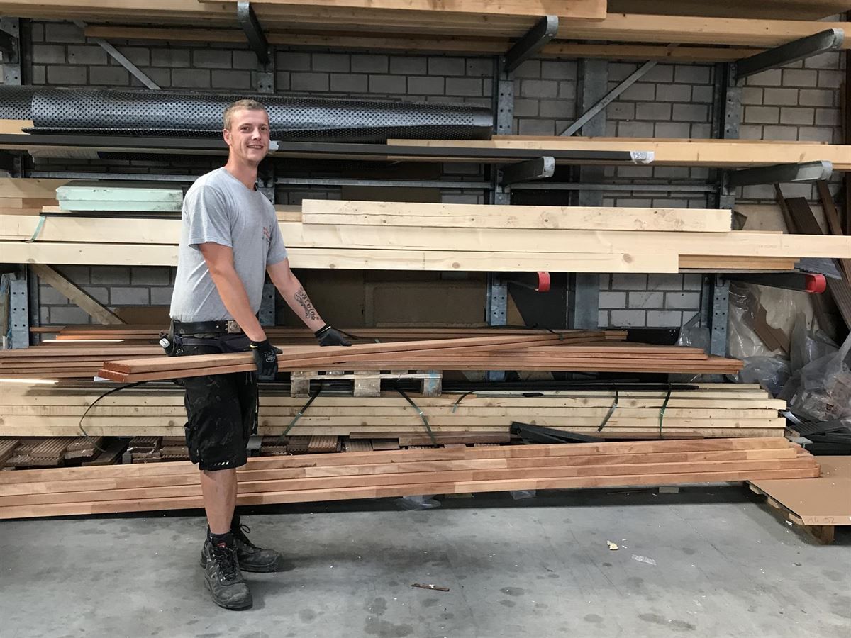 Ein Mann hält ein großes Stück Holz in einem Lagerhaus