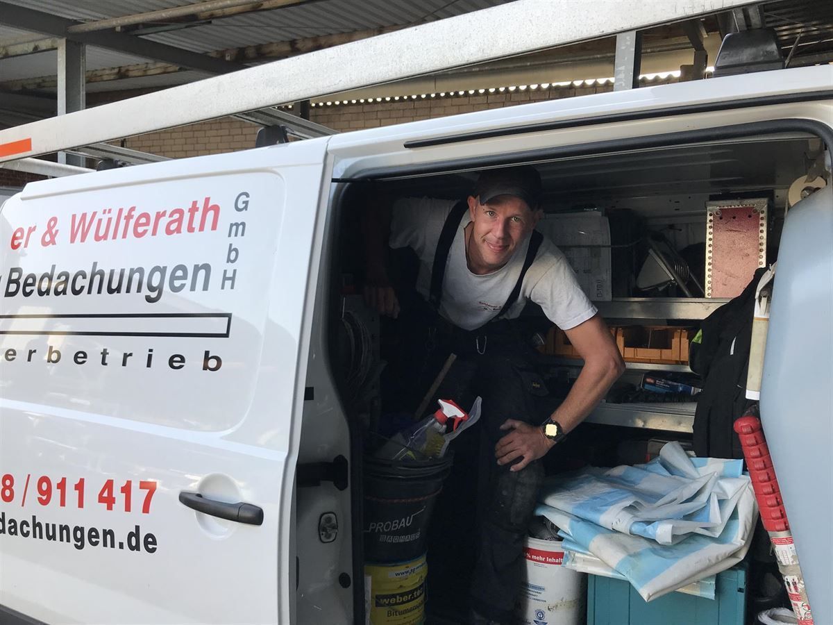 Ein Mann sitzt hinten in einem weißen Lieferwagen mit der Aufschrift „Er & Wulferath Bedachungen“