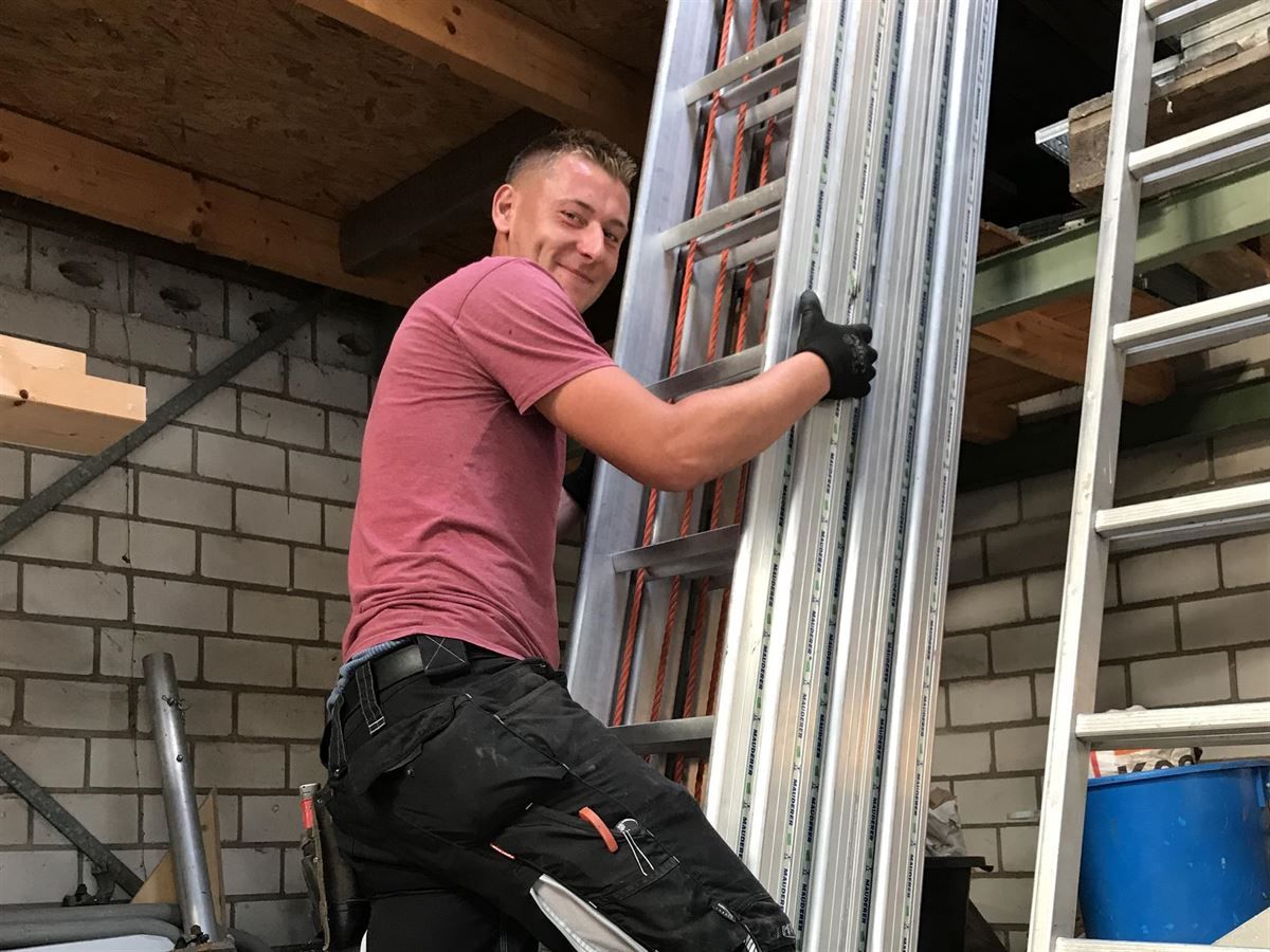 Ein Mann in einem rosa Hemd klettert eine Leiter hinauf