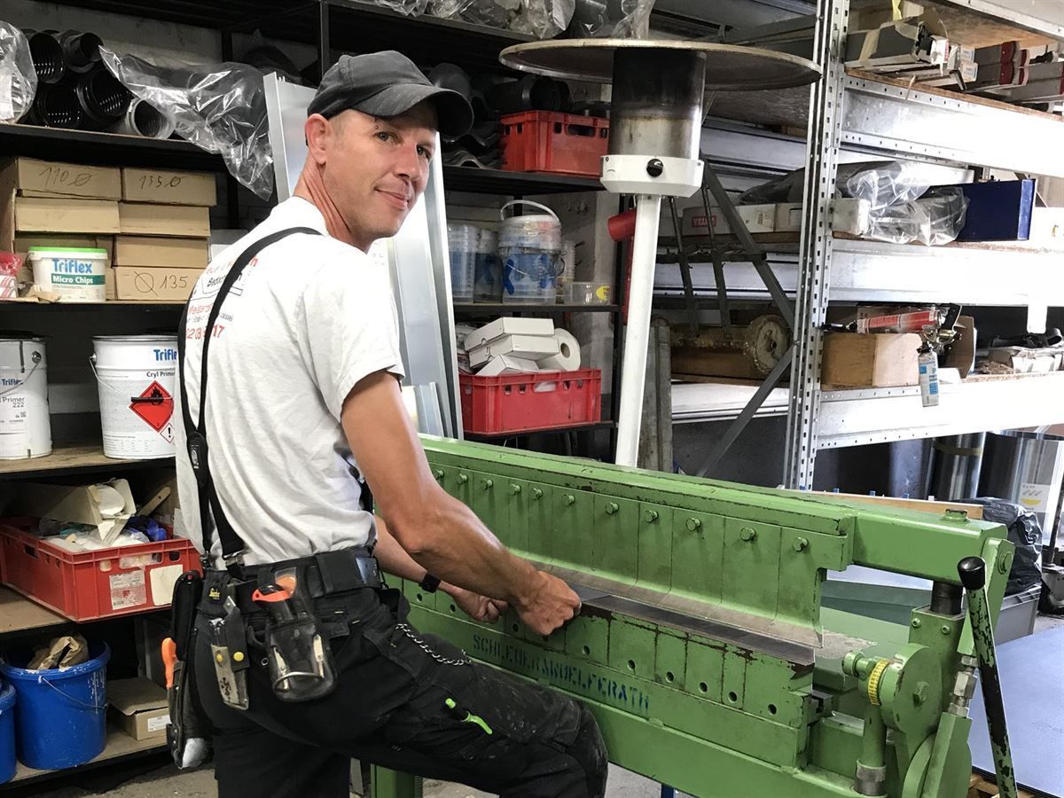 Ein Mann sitzt auf einer grünen Maschine in einer Garage
