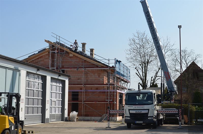 Ein weißer LKW mit dem Wort „Mann“ auf der Vorderseite steht vor einem im Bau befindlichen Gebäude