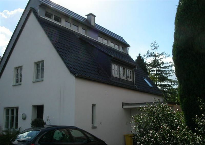 Ein weißes Haus mit einem davor geparkten schwarzen Auto