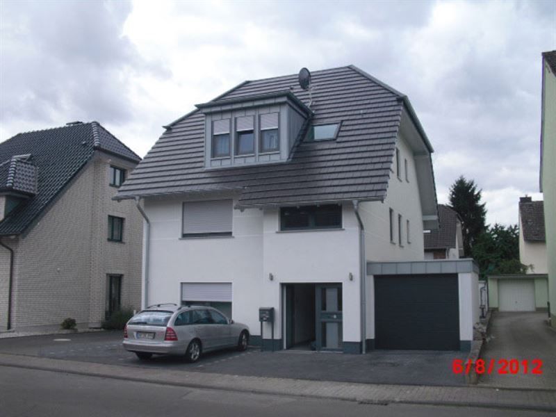 An einem bewölkten Tag parkt ein Auto vor einem weißen Haus