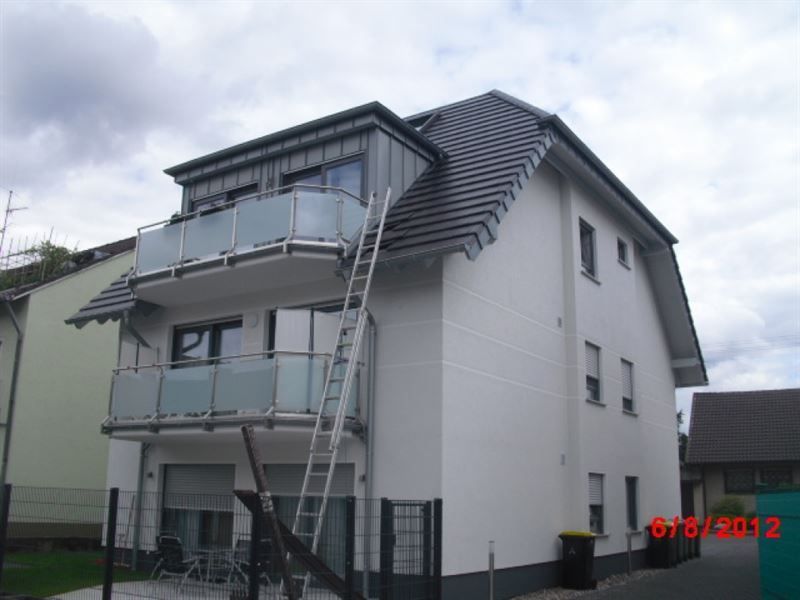 Ein weißes Haus mit einem Balkon und einer Leiter an der Seite