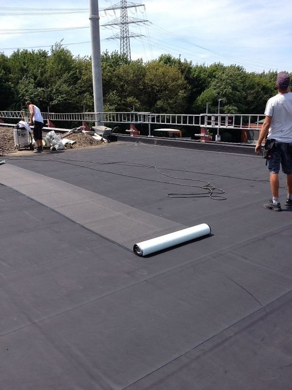 Ein Mann steht auf einem Dach mit einer Papierrolle darauf