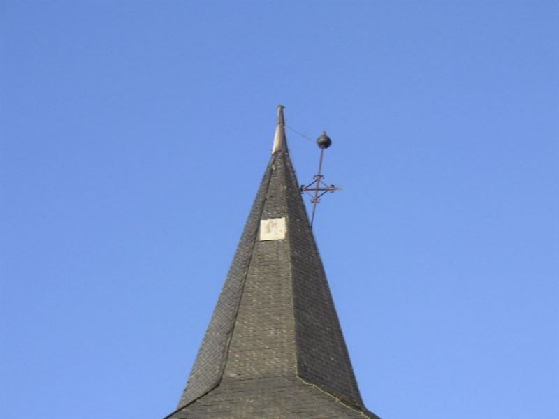 Eine Wetterfahne auf einem Kirchturm mit einer Uhr darauf