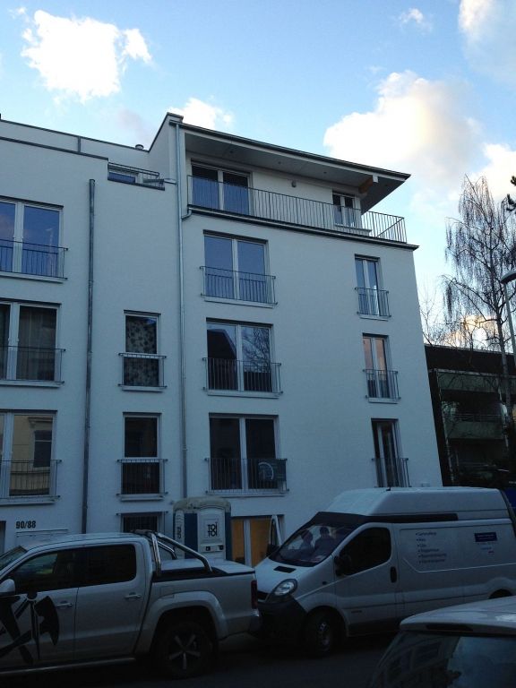 Ein weißes Gebäude mit vielen Fenstern und davor geparkten Autos