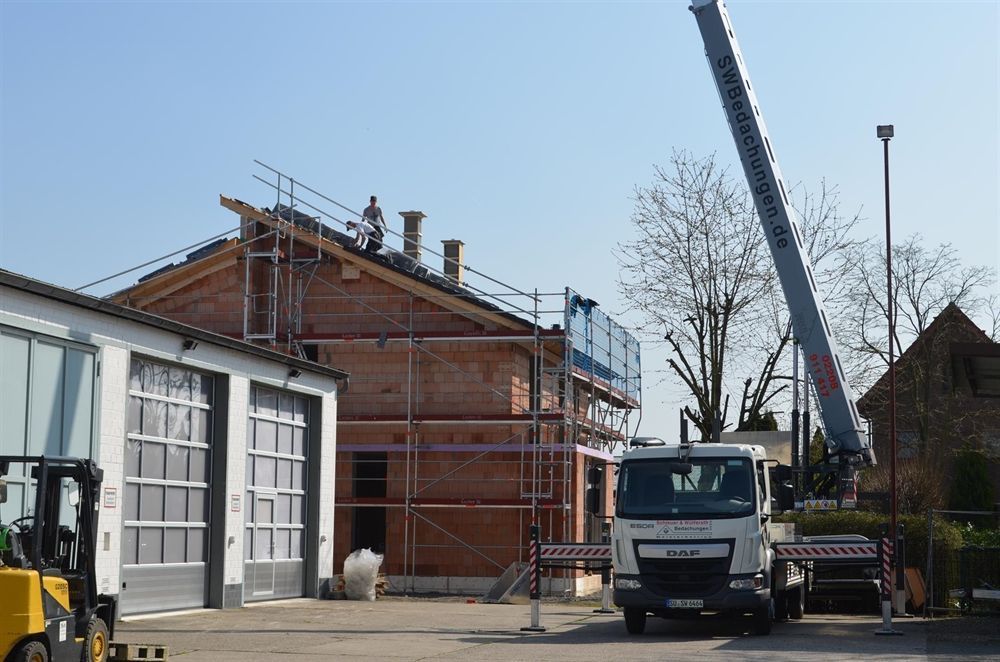 Ein weißer LKW steht vor einem im Bau befindlichen Gebäude