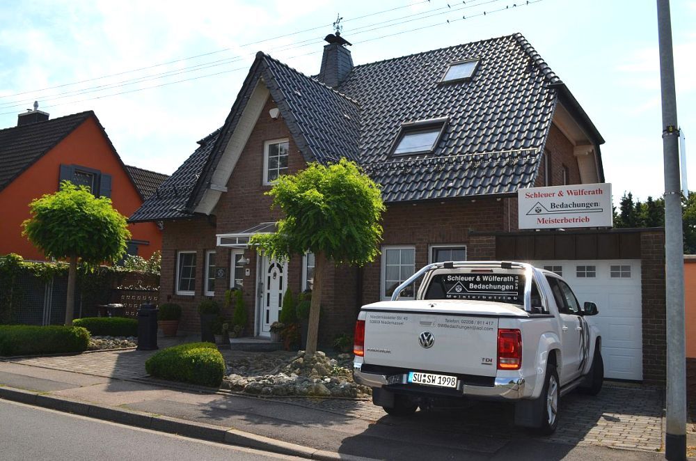 Ein weißer Lastwagen steht vor einem Backsteinhaus