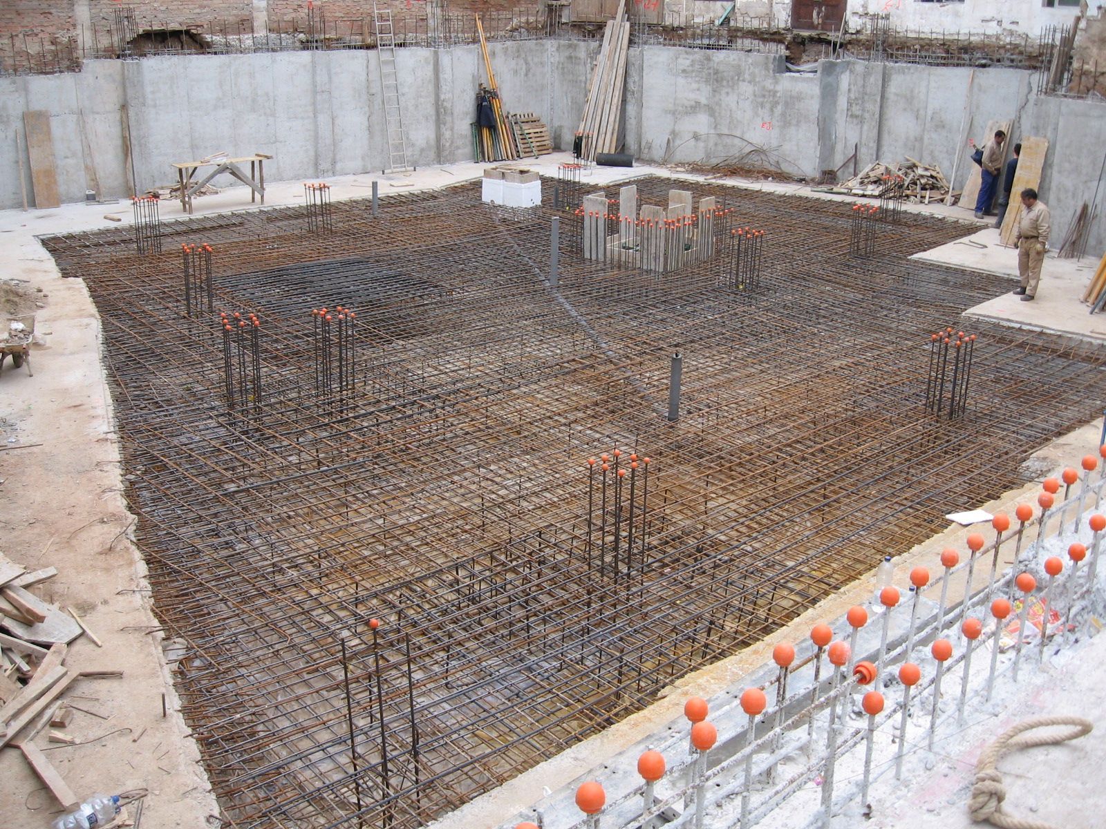 Sitio de construcción con estructura de varilla de refuerzo para una base, mostrando la base del edificio preparada.