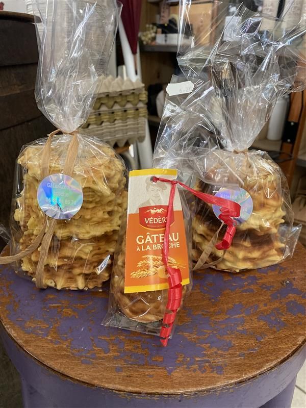 Une personne verse de la pâte sur une broche tournante au-dessus d'un feu ouvert pour cuire un gâteau sakotis traditionnel lituanien.