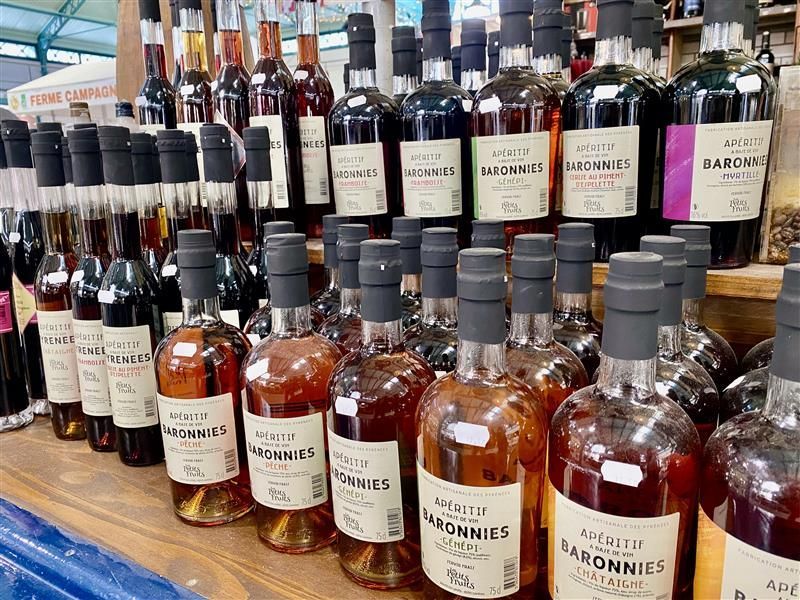 Du vin rouge est versé d'une bouteille dans un verre, avec d'autres verres et bouteilles de vin remplis en arrière-plan.