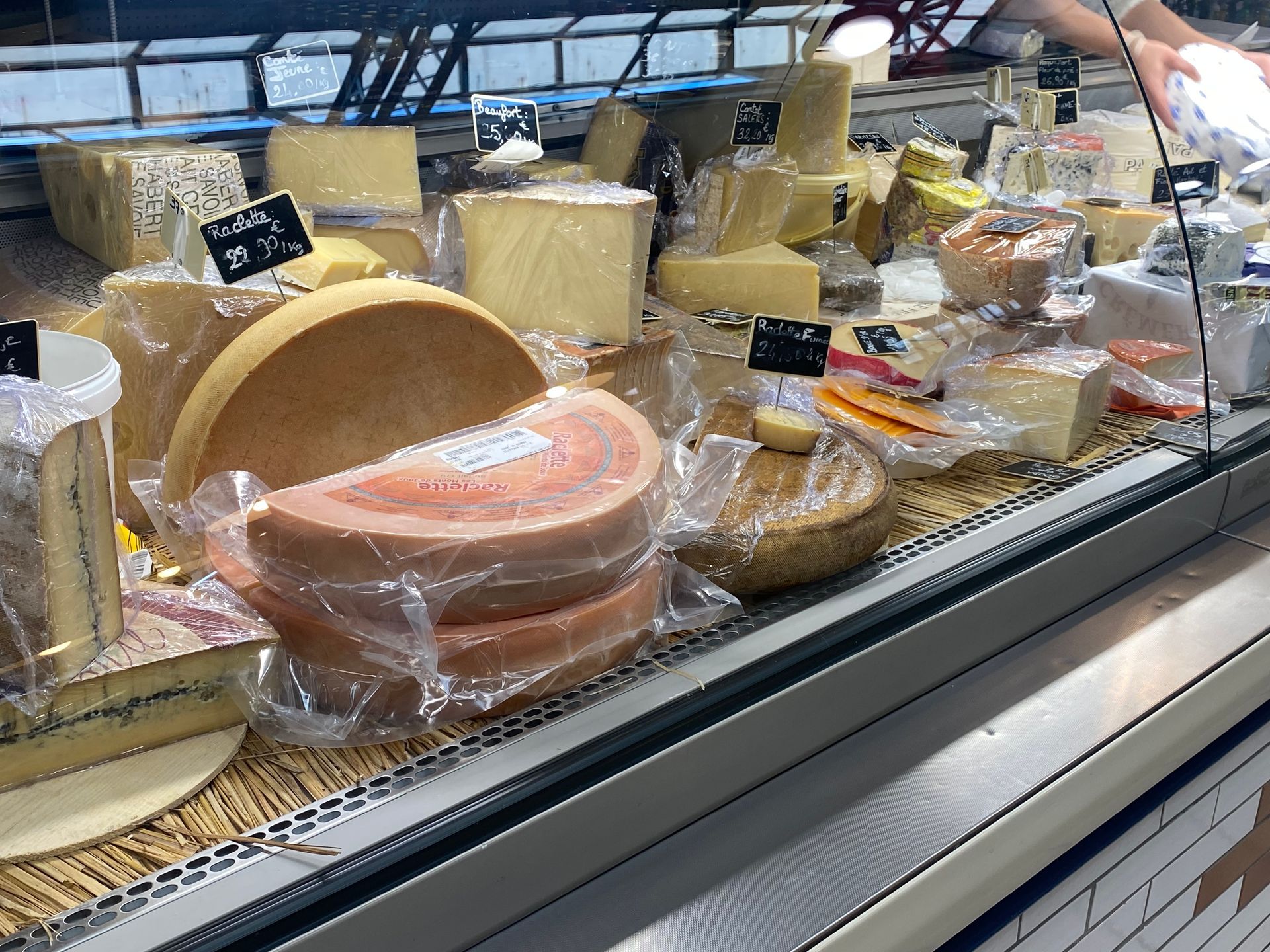 Une vitrine réfrigérée remplie d'une variété de fromages emballés, dans une épicerie fine ou un marché.