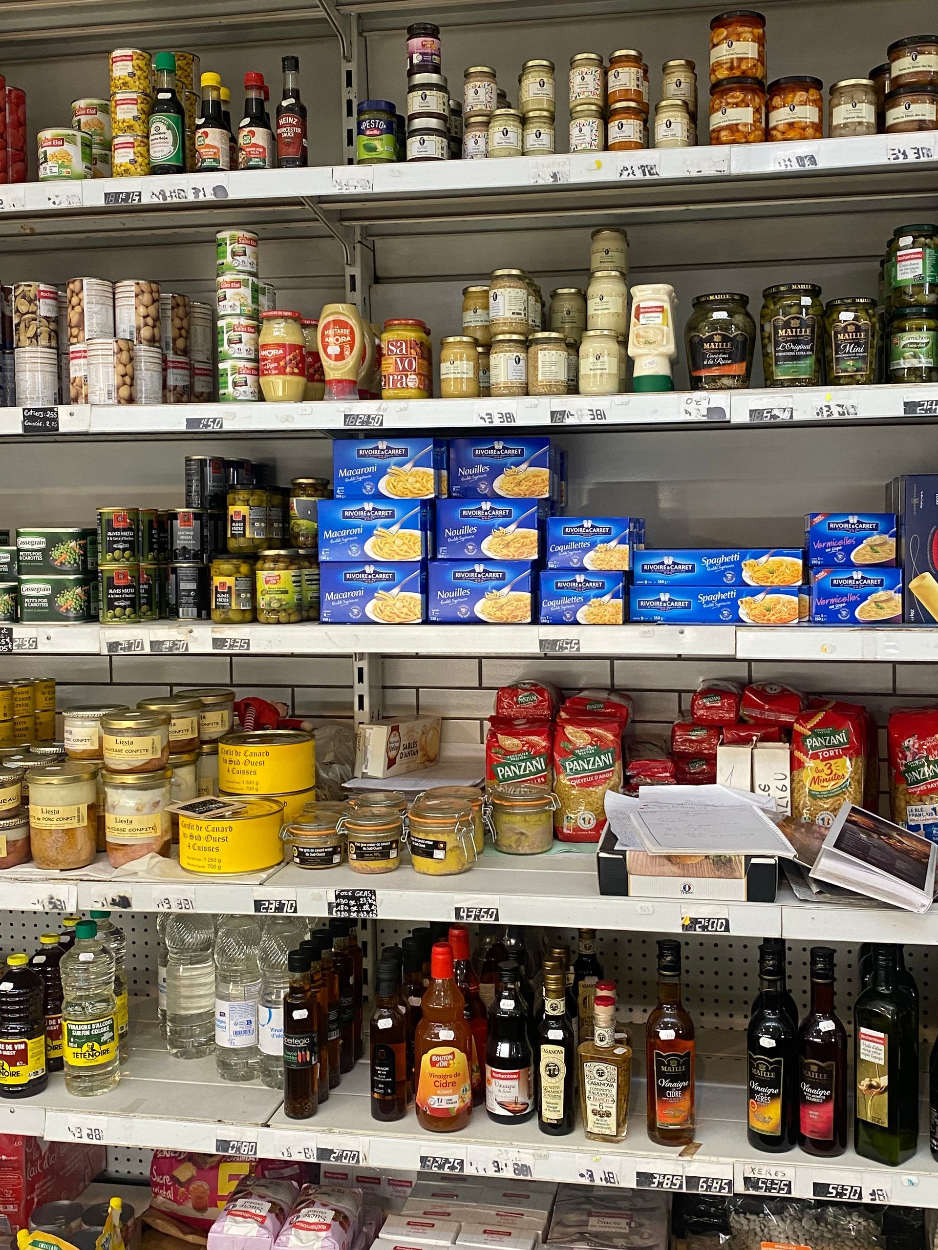 Des étagères remplies de divers produits alimentaires, notamment des bocaux, des produits en boîte, des condiments et des bouteilles d'huile de cuisson.