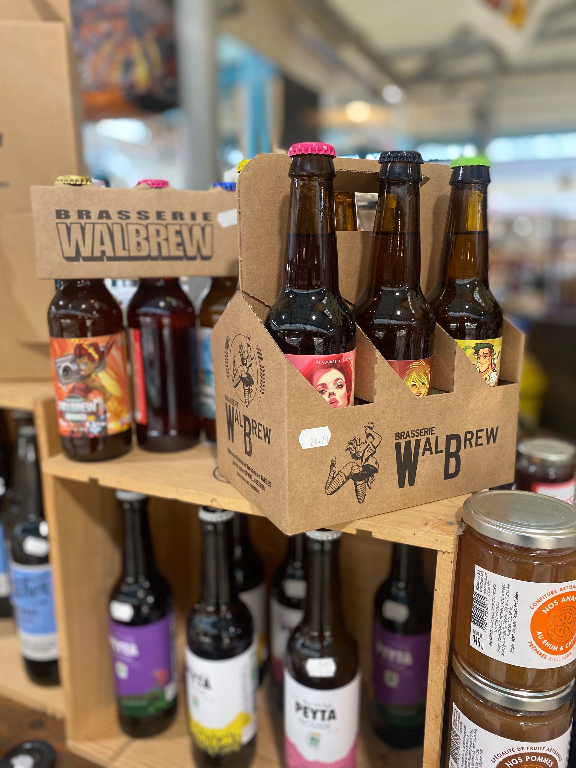 Des paquets de six en carton et des bouteilles individuelles en verre de bières artisanales Walbrew et Piyta sont présentés sur des étagères en bois.