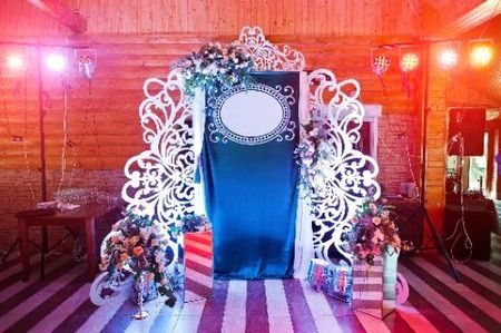 A wooden arch decorated with flowers and gifts in a room.