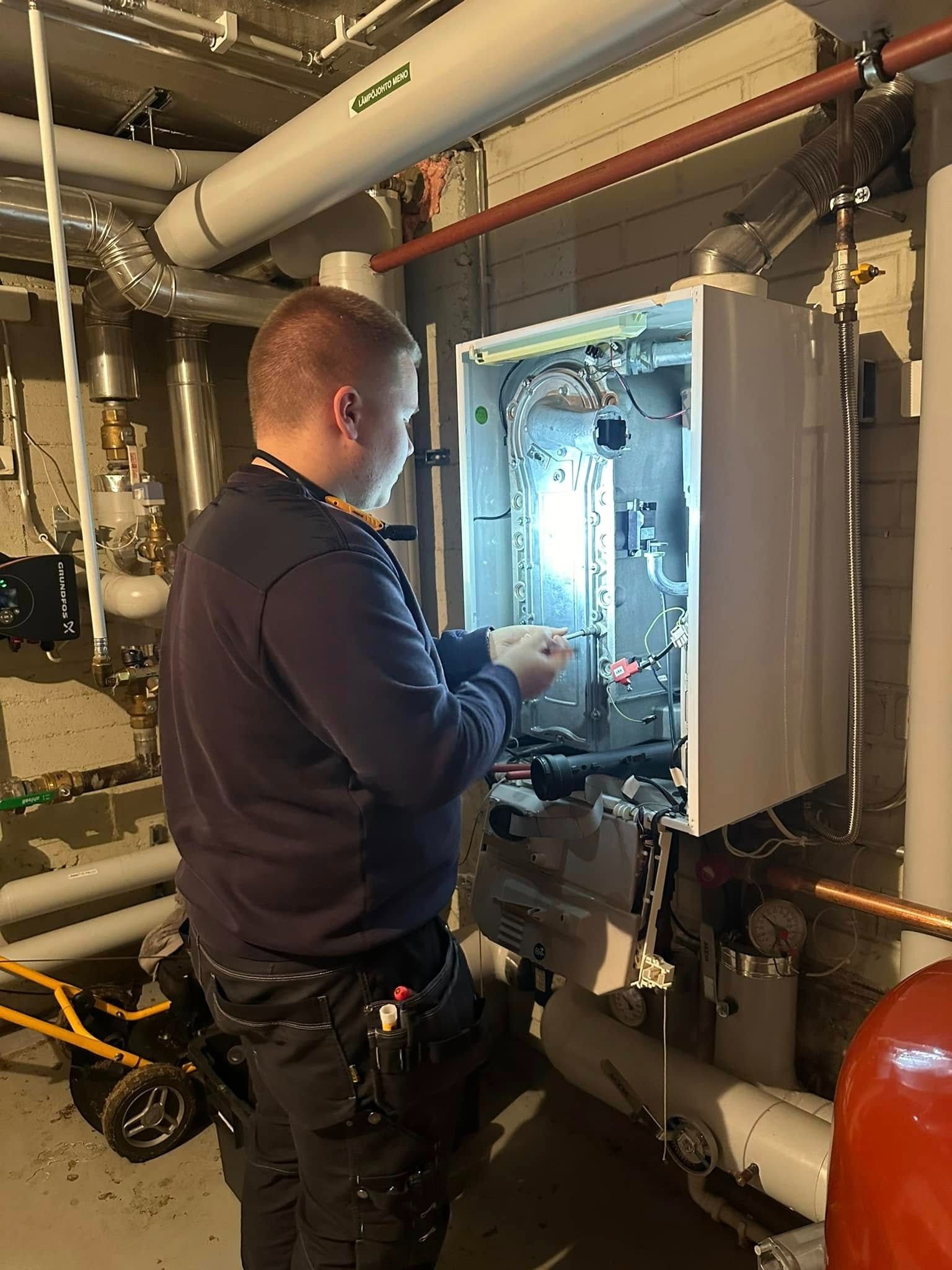 Henkilö työskentelee lämmitysjärjestelmän parissa sisätiloissa.