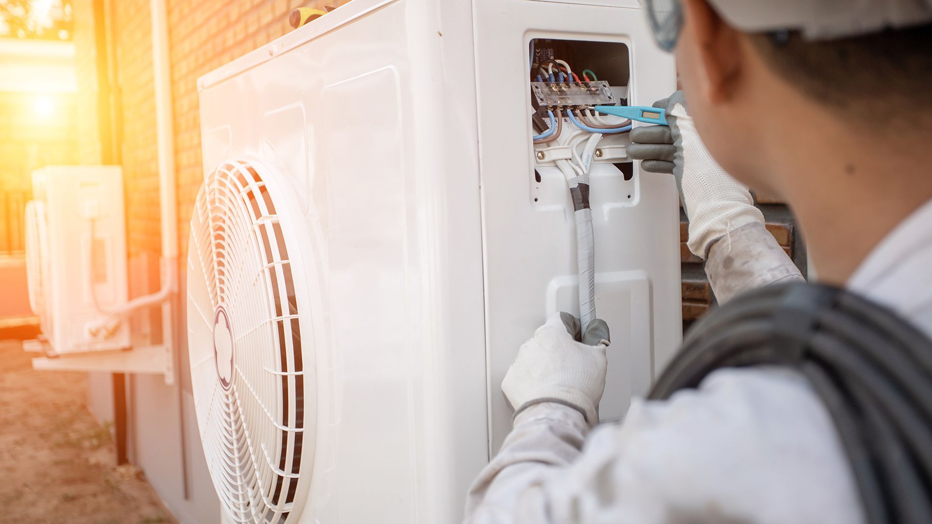 LVI-asentaja työskentelee ulkoilmastointilaitteen parissa. Käyttää työkalua ja lankaa.