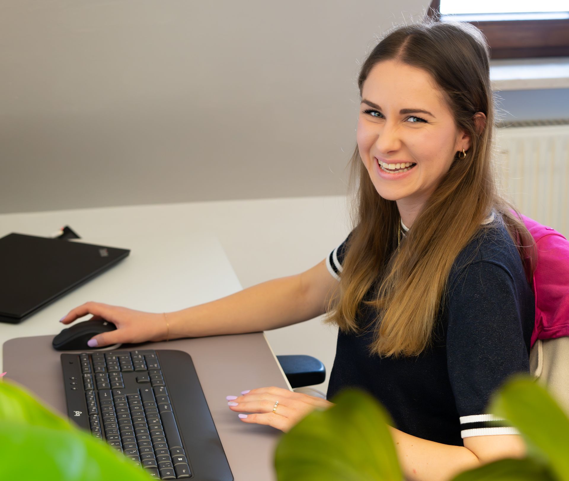 Ein Kind mit lockigem Haar betrachtet ein Buch, das von einer unsichtbaren Person an einem Tisch gehalten wird.