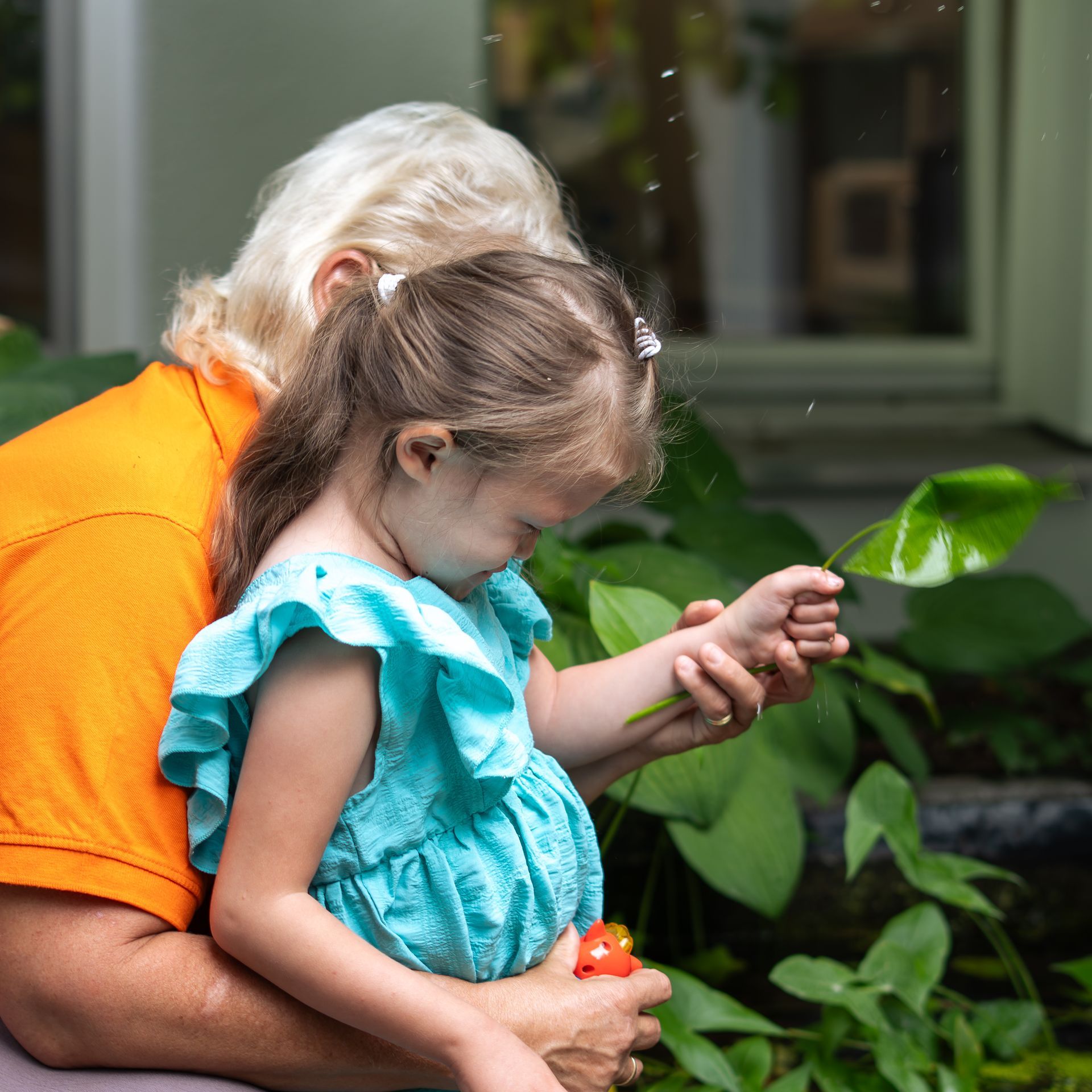 Mädchen benutzt Stethoskop an einem Teddybären neben einer medizinischen Fachkraft, farbenfroher Spielzimmerhintergrund.