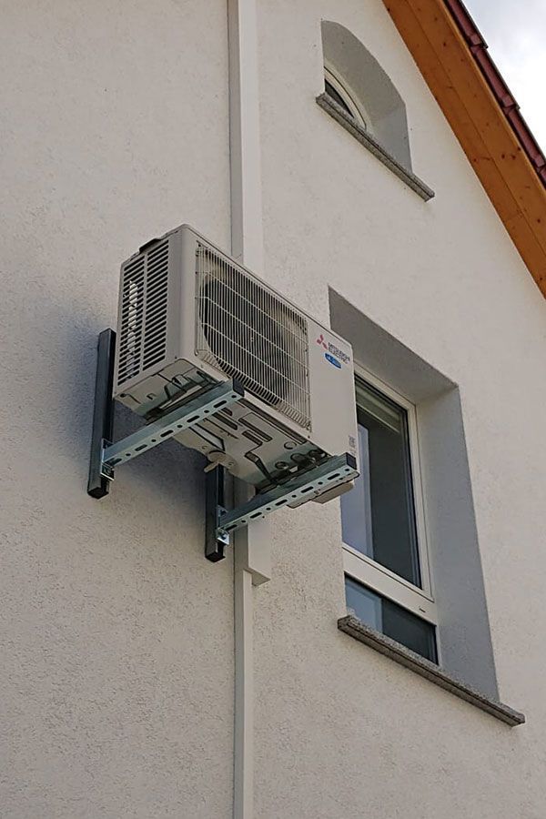 Eine Klimaanlage wird an der Seite eines Gebäudes neben einem Fenster montiert.