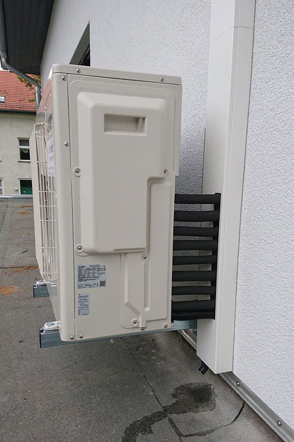An der Seite eines Gebäudes steht eine weiße Klimaanlage.