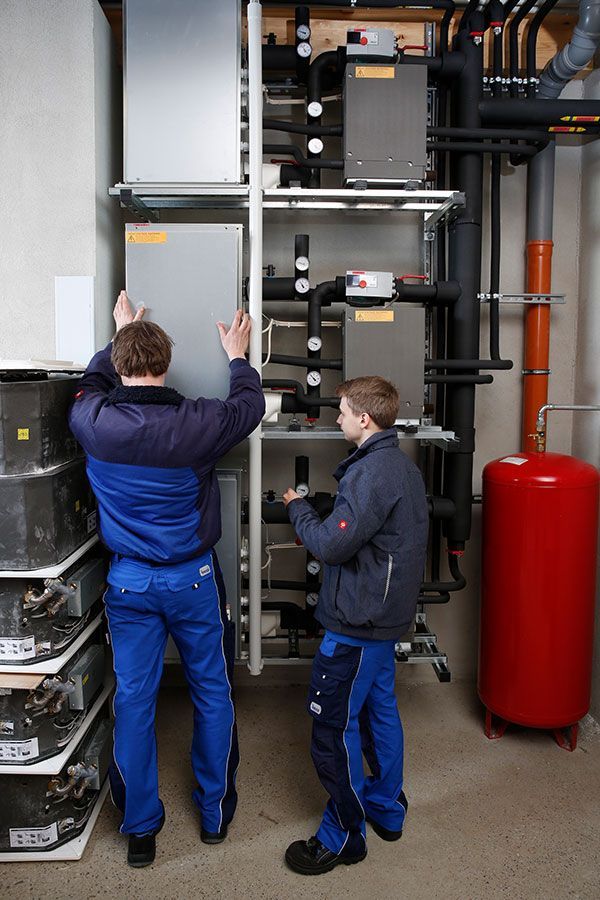 Zwei Männer arbeiten in einem Raum an einer Maschine.