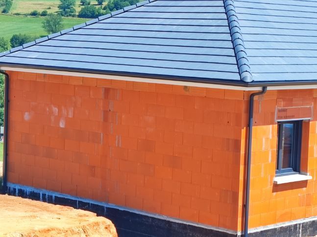 Installation de gouttières de couleur noire sur une construction neuve