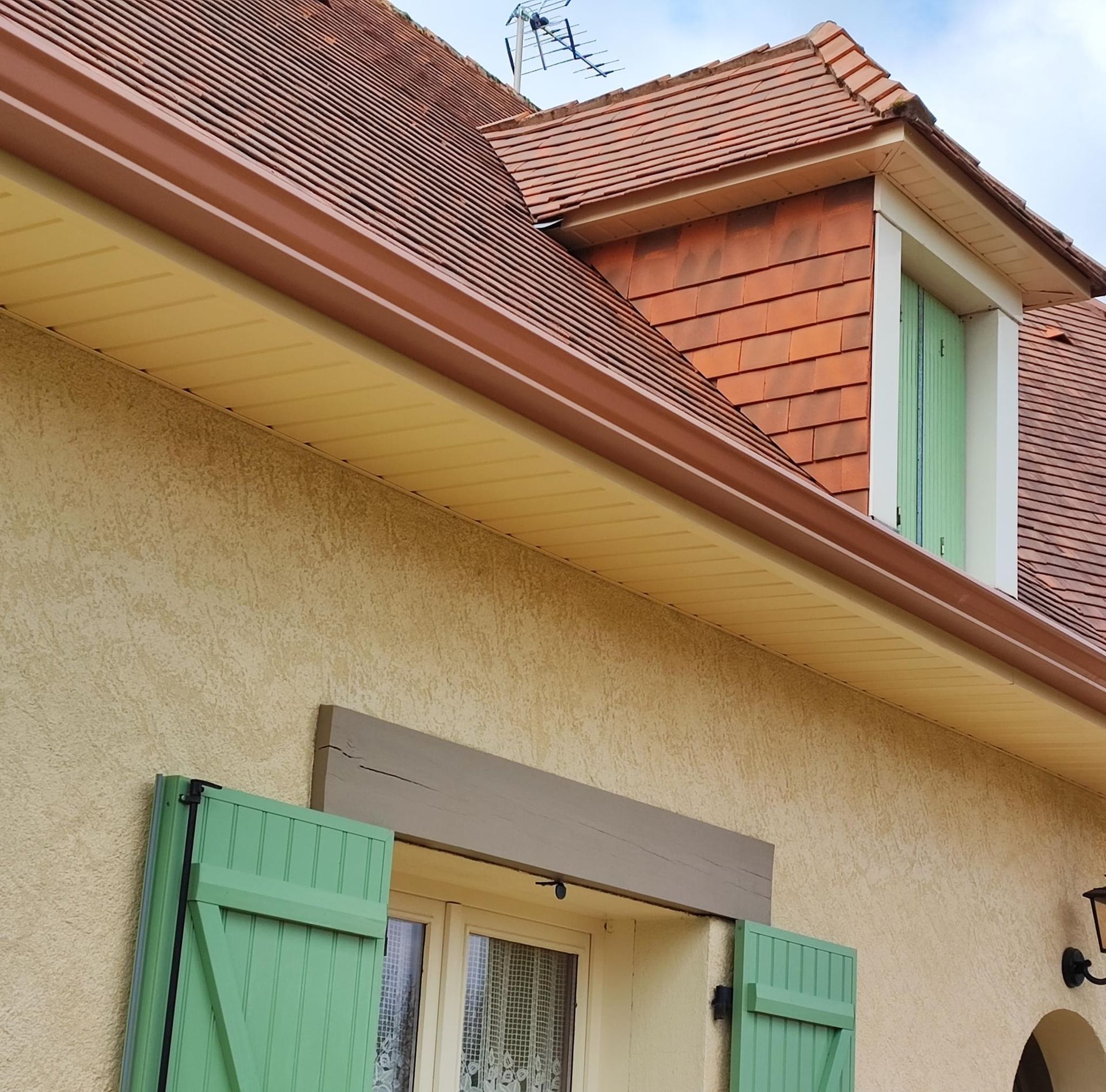 Gouttières en aluminium brun sur une maison à la toiture en tuile