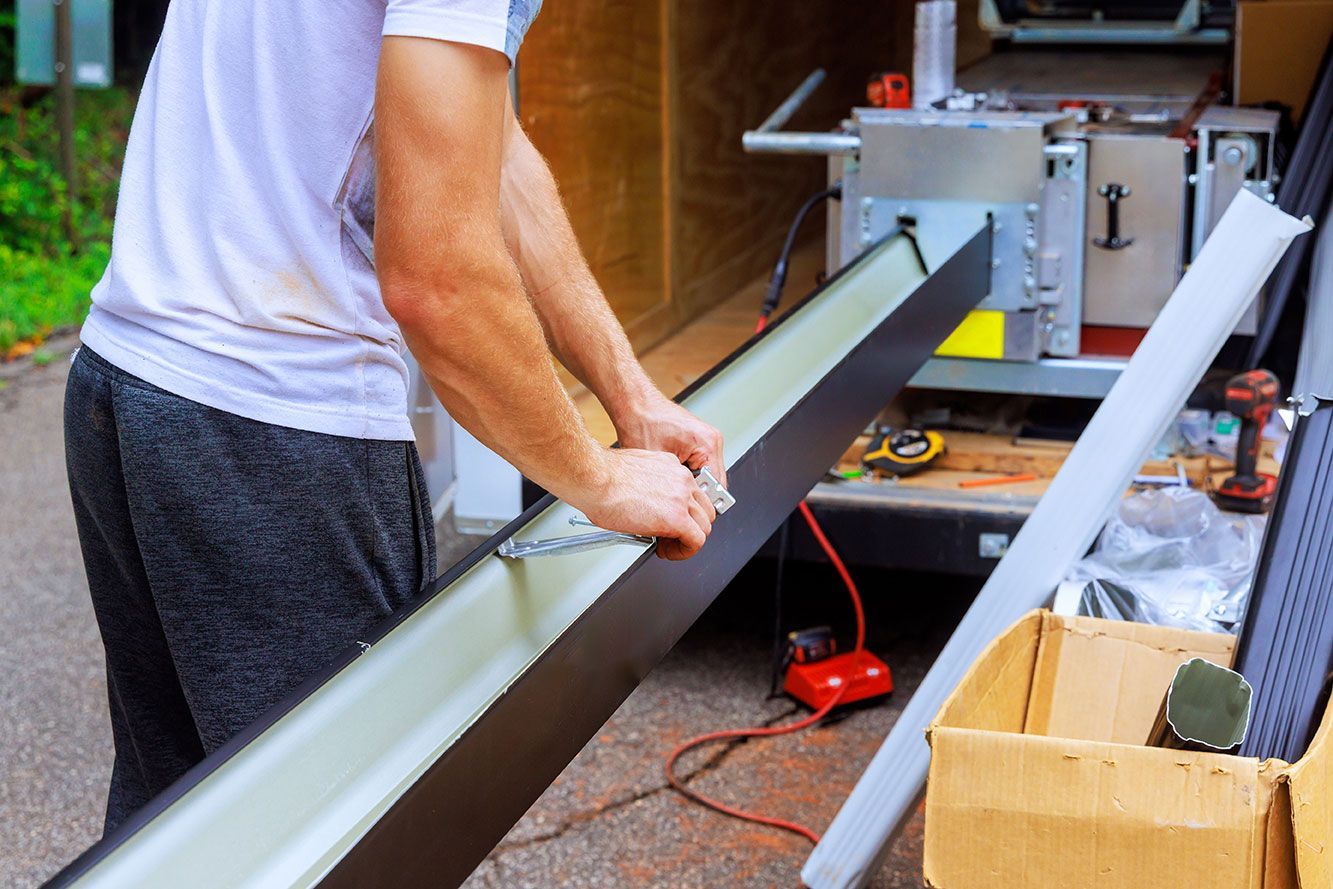 Ouvrier qui prépare une gouttière à l'arrière de son camion