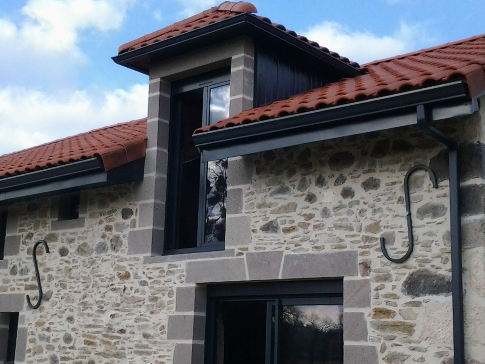 Gouttière en aluminium gris anthracite sur la façade d'une maison, descentes rectangulaires et lambris de sous-face