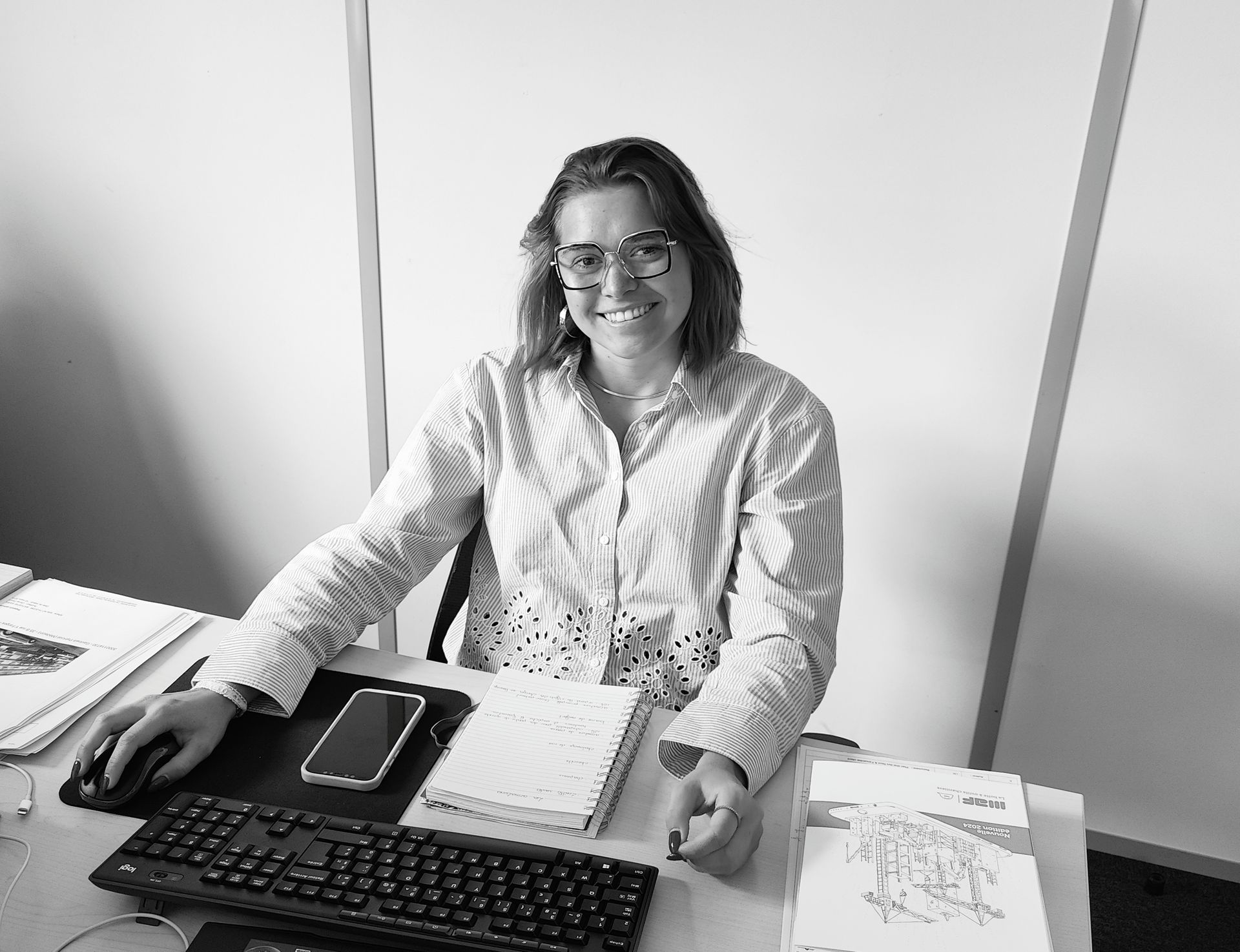 Candice Volk à un bureau, portant des lunettes et une chemise devant son ordinateur.