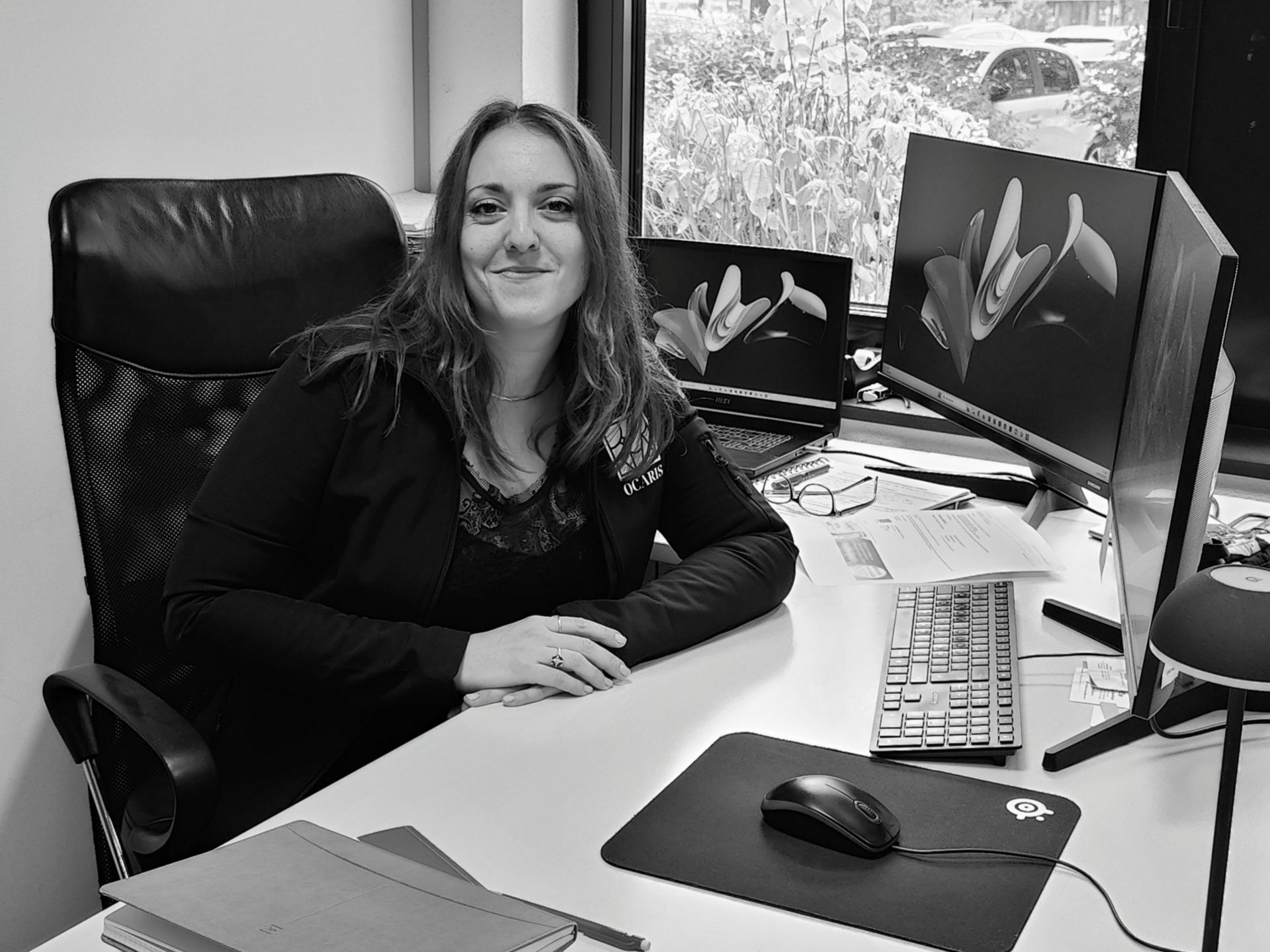 Lydia Marreiro assise à un bureau souriante, devant un ordinateur.